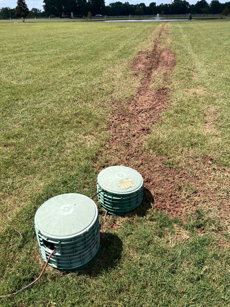 Septic drain line risers and buried connection trench in a finished yard.
